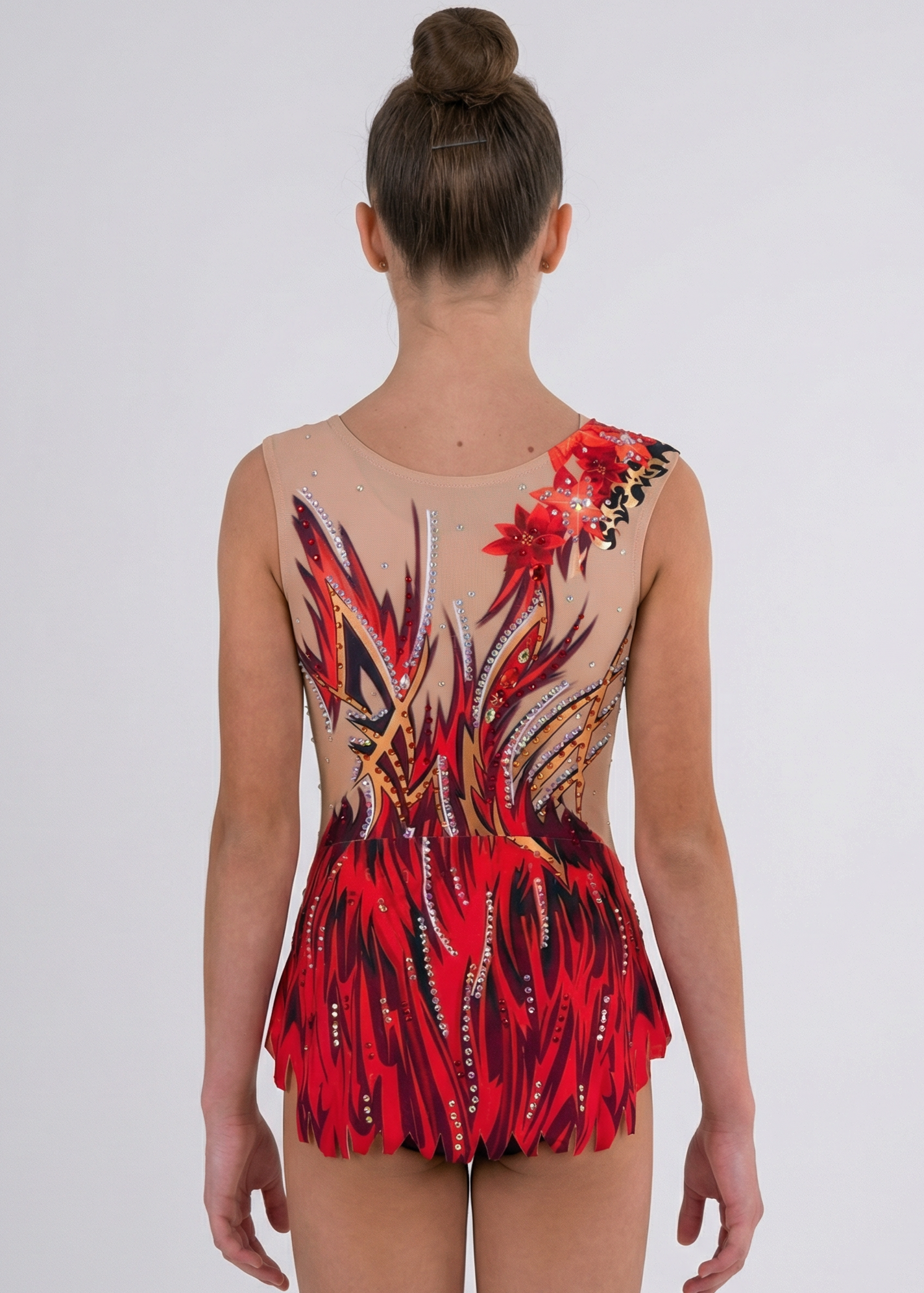 Maillot de gimnasia rítmica visto por la espalda con base clara, pedrería dispersa y llamas rojas y negras en diseño fluido.