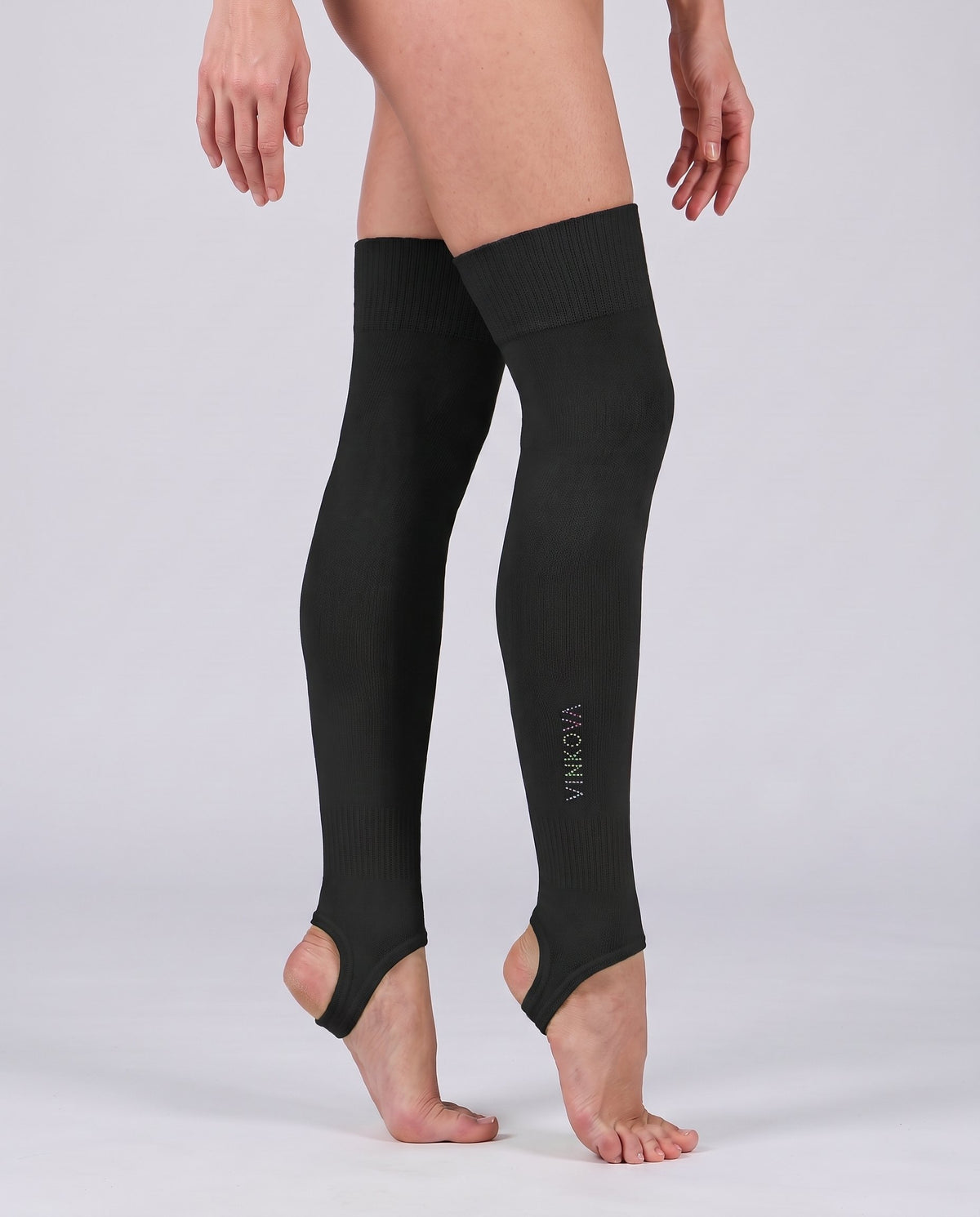 Ginnasta in mezza punta con scaldamuscoli lunghi da ginnastica ritmica Vinkova, colore nero, fino a metà coscia