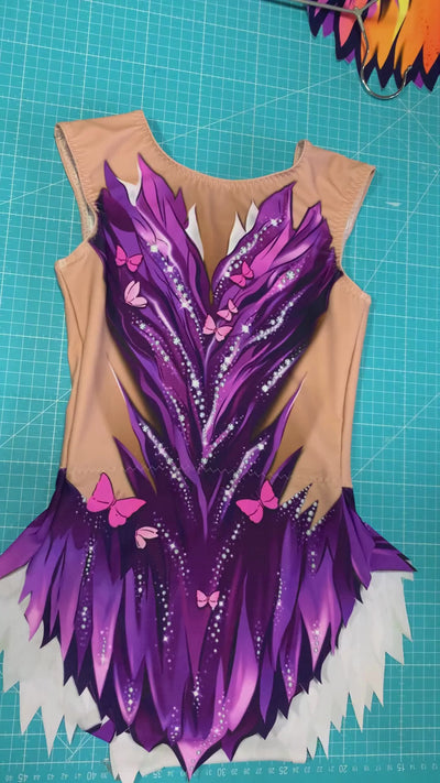Maillot rítmico elástico con motivos de plumas violetas y pequeñas mariposas para máxima elegancia en tapiz.